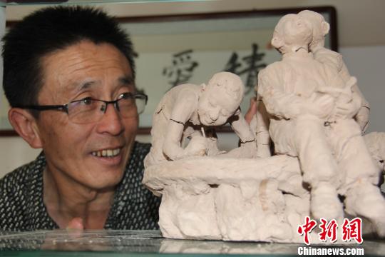 图为赵铁军正在观看制作完成的人物泥塑。 郭惠民 摄 图为赵铁军正在观看制作完成的人物泥塑。 郭惠民 摄