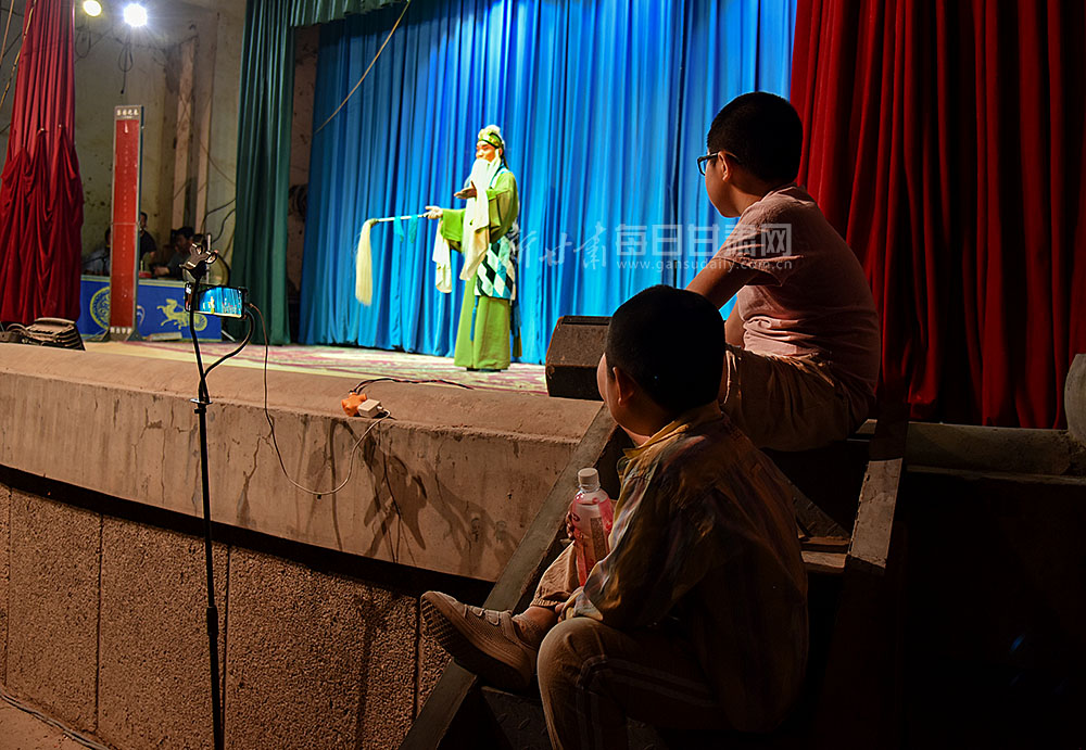 圖為“小戲迷”坐在舞臺邊上認真觀看演出.jpg