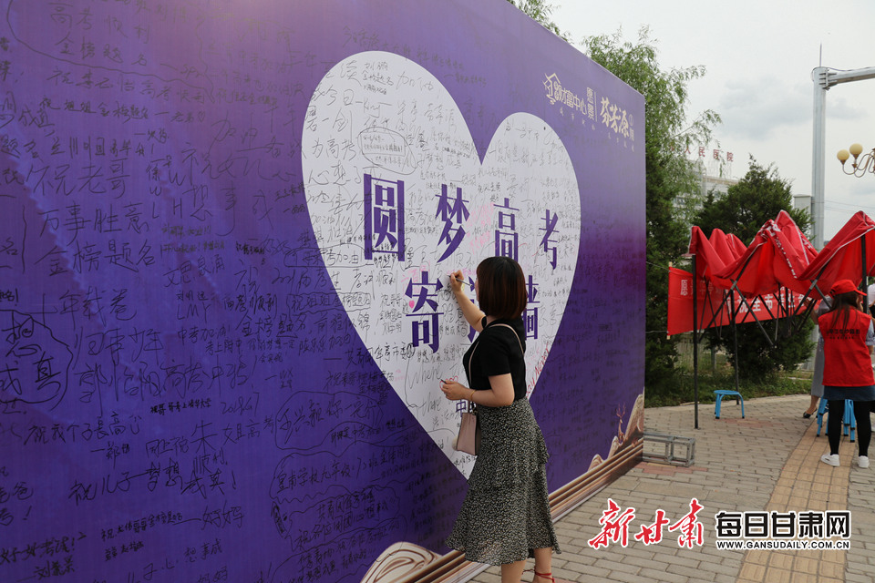 离考场不远处的一处寄语墙,一位家长正在为考生书写寄语.