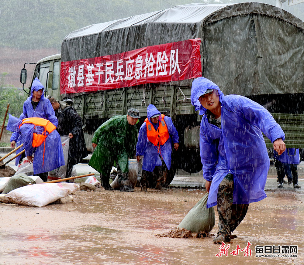 日,甘肃陇南市徽县武装部民兵抗洪抢险突击队员正在扛运沙包加固堤坝