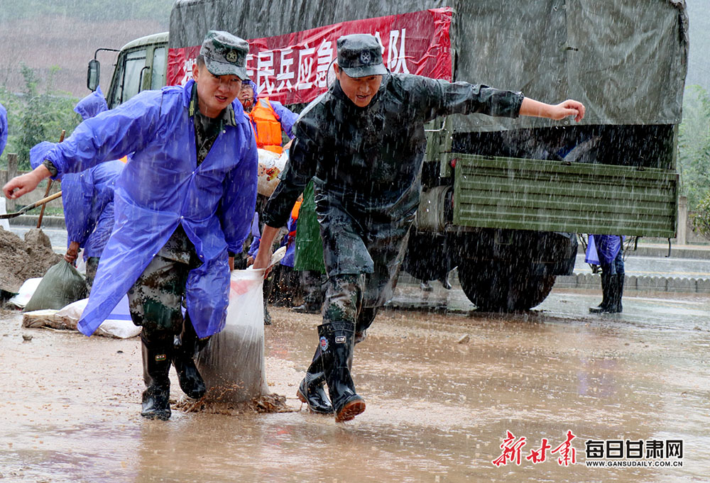 8月16日,陇南市徽县武装部民兵抗洪抢险突击队员正在扛运沙包加固堤坝